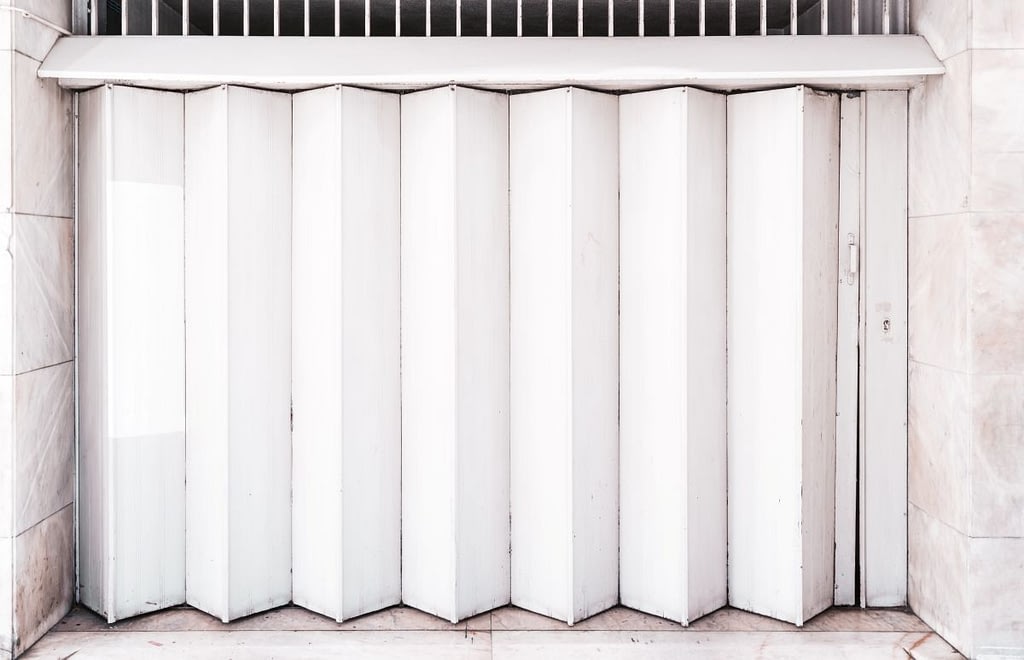A Garage or other entrance closed metal gate texture with white vertical fanfold lines of the door