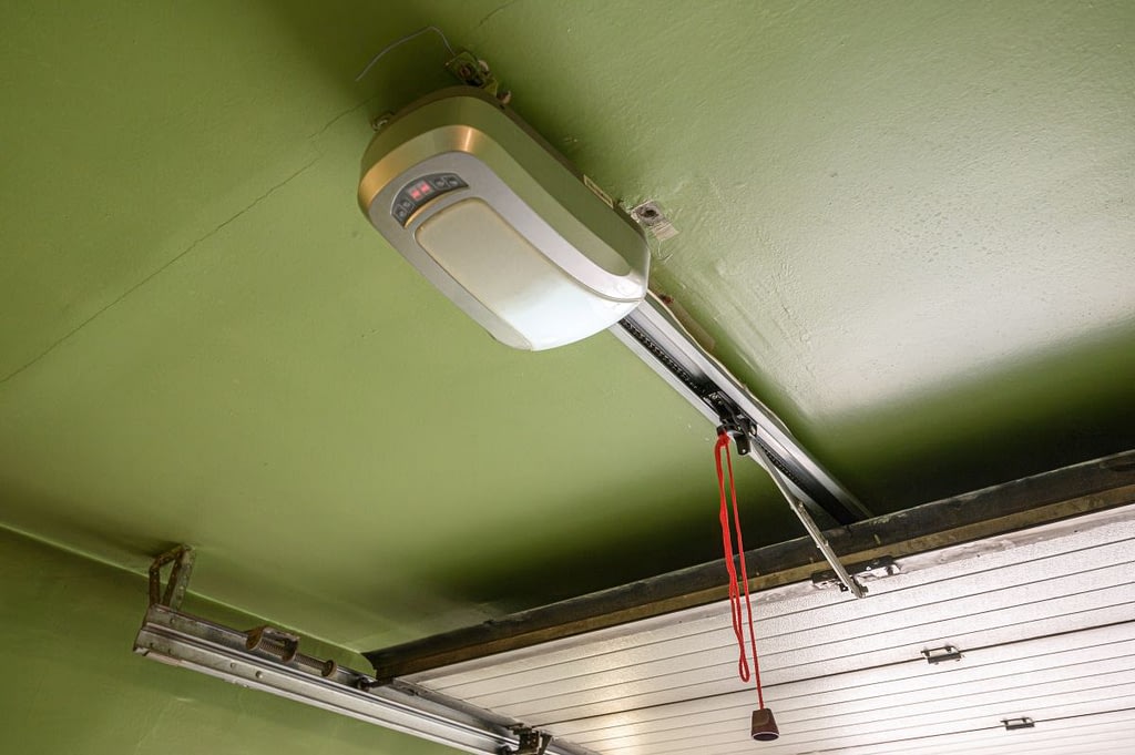 A ceiling-mounted garage door opener with a metallic casing, control panel