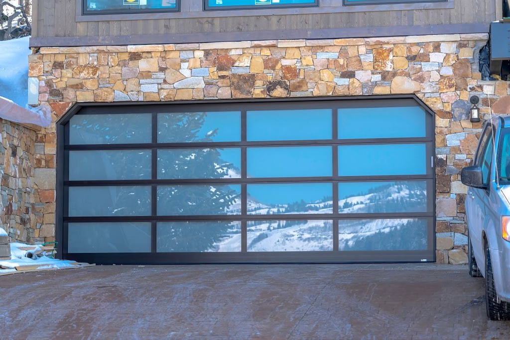 Garage door with glass panes reflecting a snowy hill landscape