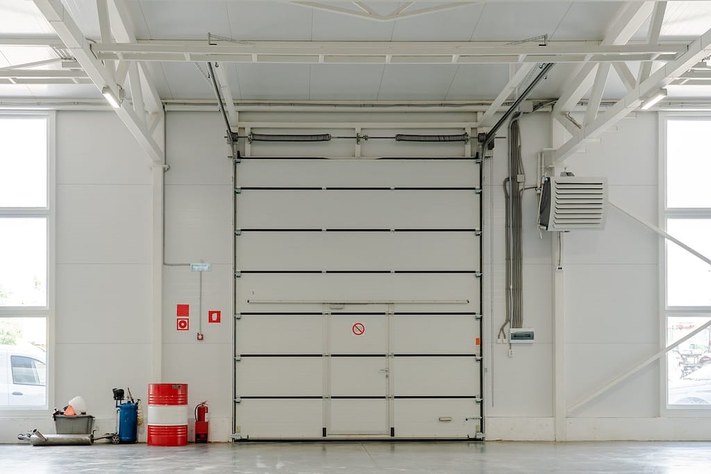 Industrial garage door in modern warehouse interior with fire safety system, HVAC ventilation, engineering infrastructure and storage logistics