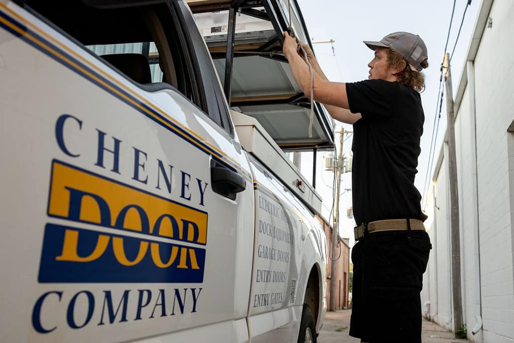 Garage door spring replacement Cheney Door Company technician with black clothes next to branded van