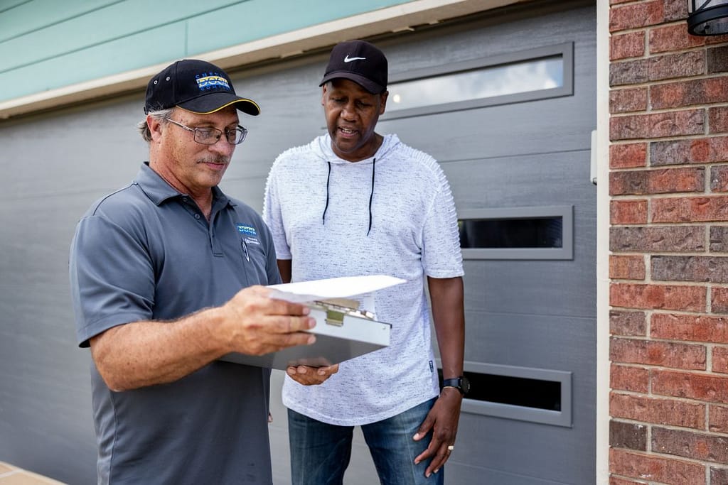 carriage house garage doors Cheney Door worker and client talking in front of garage door