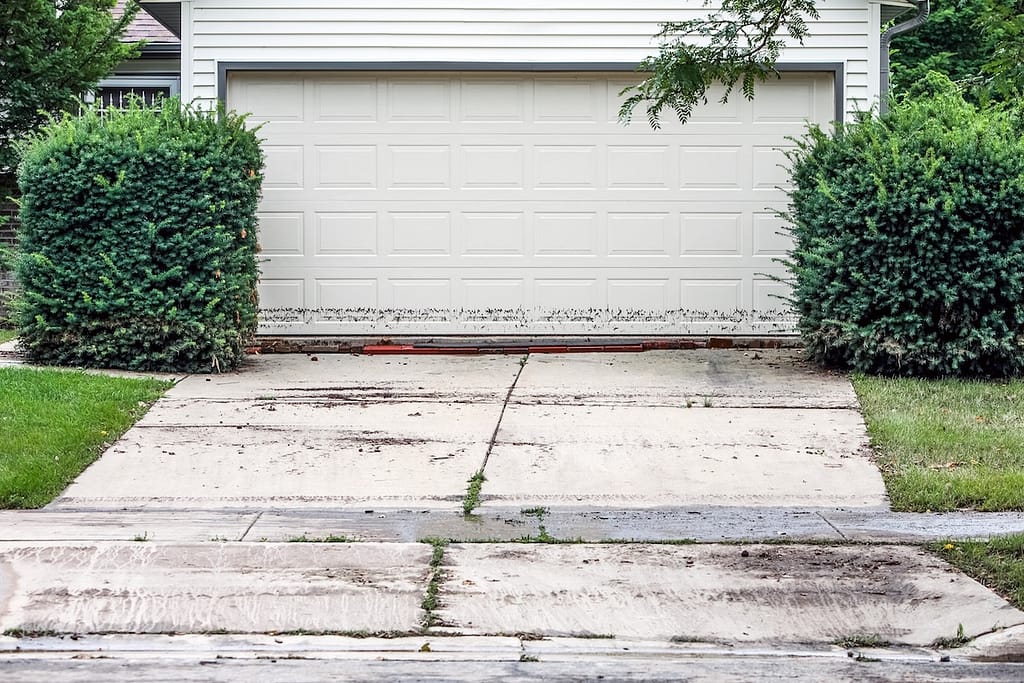 A white, clean garage door with mud splatters at the bottom