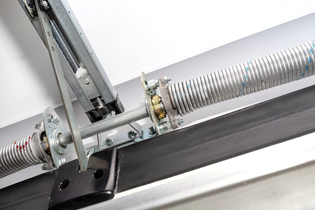 Springs tensioning the garage door mechanism, view from the inside, visible rail with chain and spring protection.