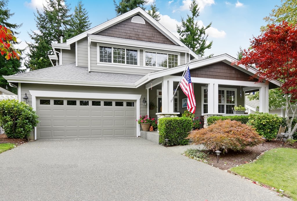 Nice curb appeal of grey house with garage and driveway.